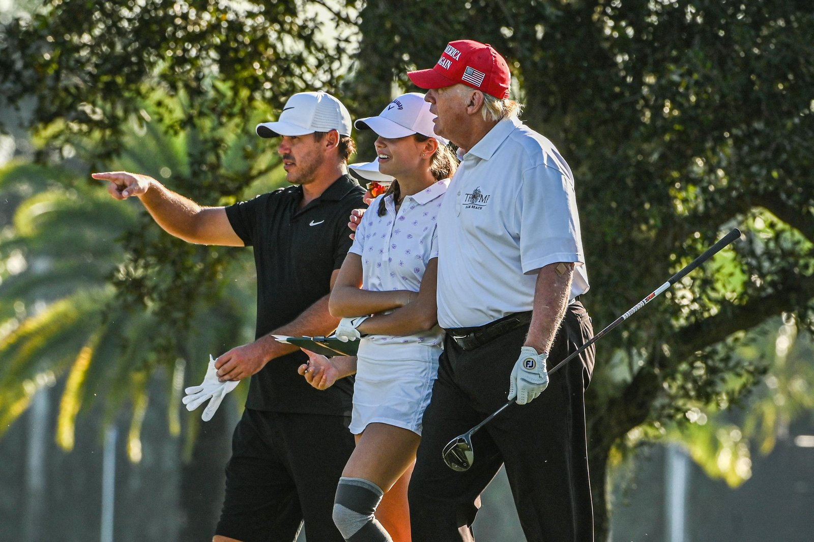 Donald Trump, US golfer Brooks Koepka and Trump's granddaughter Kai Trump play golf at Trump National Doral Miami golf club on October 27, 2022 in Miami, Florida