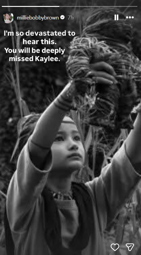 A black-and-white image from "Godzilla vs. Kong" shows Kaylee Hottle as Jia lifting a Kong figurine while looking upward. Millie Bobby Brown shared the still on her Instagram Story alongside a message mourning Kaylee after news of the actress's death broke.