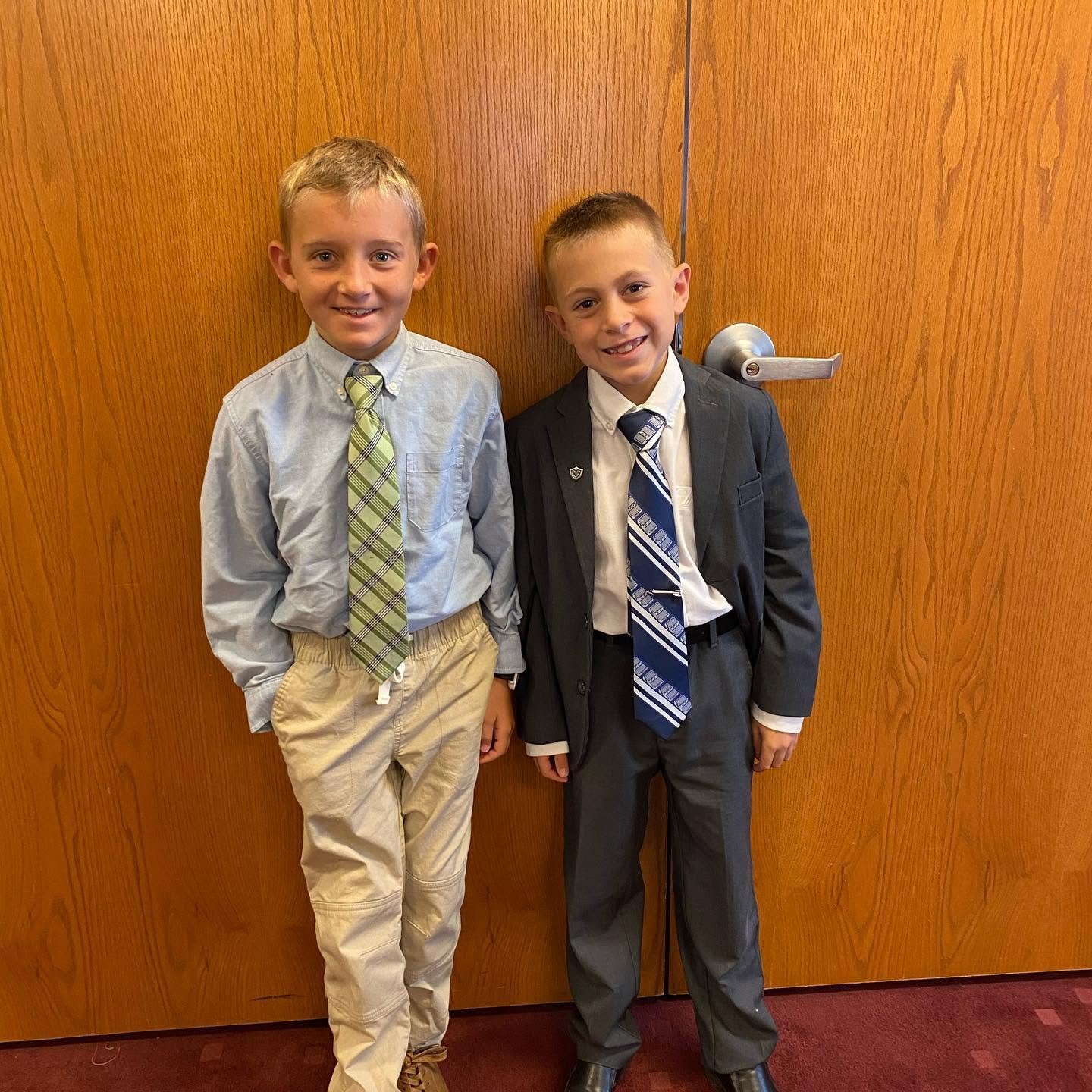 The two younger boys show off their matching suits and bright grins, capturing the playful camaraderie shared among the brothers.